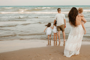 Family of five walking along the beach together, reflecting the family-centered values behind August & Ivy parenting products.