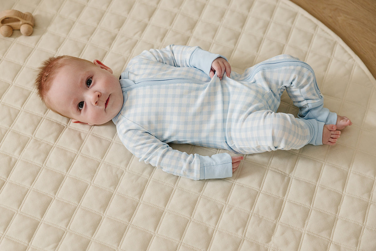 August & Ivy organic Pima cotton zip romper for babies, shown in soft fabric with a front zipper and snap buttons.