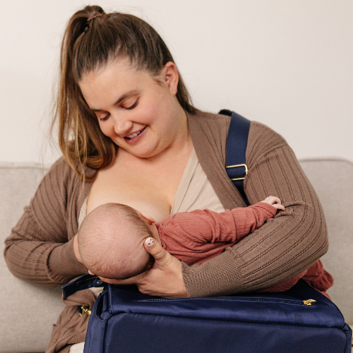 Mother feeding baby confidently in public with nursing diaper bag