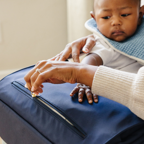 Mom placing ergonomic diaper bag on lap for breastfeeding support