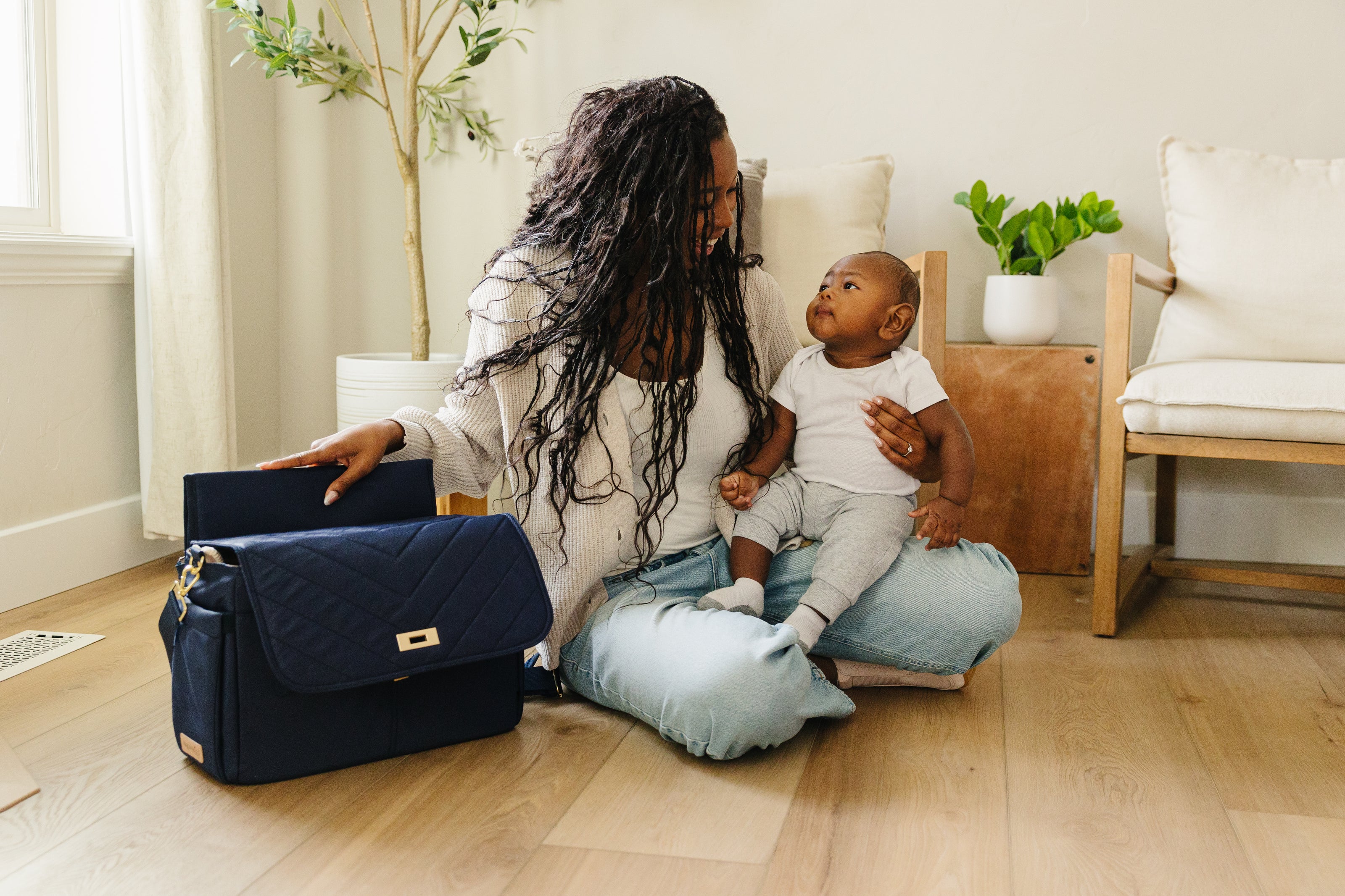 Mom sitting with baby beside the August & Ivy IvyGo premium structured diaper bag designed for modern parenting