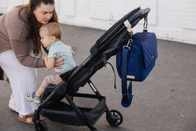 August & Ivy IvyGo diaper bag attached to stroller with universal stroller clips for hands-free outings